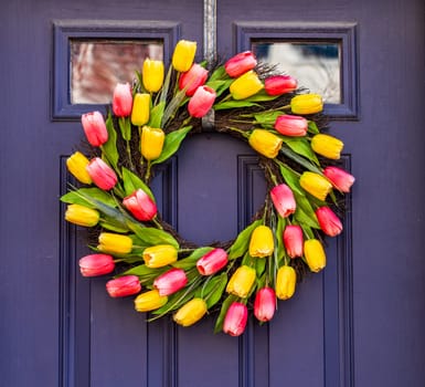 Arrangement of tulips in circular wreath on exterior door marking the start of Easter and springtime