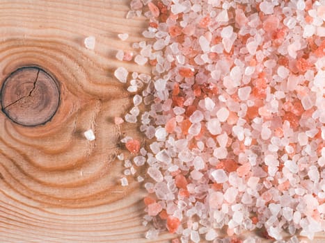 Himalayan pink salt in crystals on wooden background. Copy space