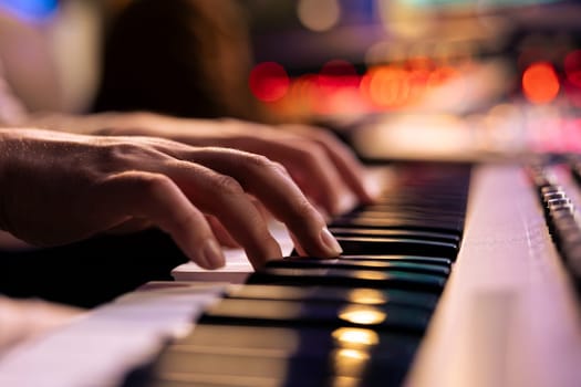 Musician playing electronic keyboard synthesizer in professional studio, creating songs and working with producer on new album. Talented singer composing music on electronic keyboard. Close up.