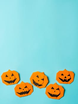 Halloween concept. Paper origami pumpkin on bright blue background. Simple idea for halloween - easy made paper pumpkins on light blue color background. Copy space for text. Banner. Vertical