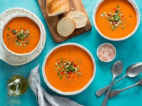 Gaspacho soup on blue tabletop. Three bowls of traditional spanish cold soup puree gaspacho or gazpacho on bright blue background. Top view or flat lay.