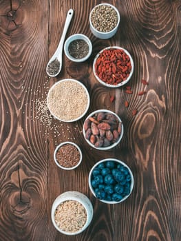 Various superfoods in small bowl on wooden table.Selection super food.Superfood as blueberry, chia, raw cocoa bean, goji, hemp seeds, quinoa, brown rice. Copy space.Top view or flat lay.Vertical