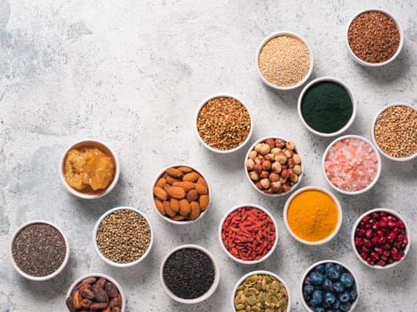 Various superfoods in smal bowl gray concrete background. Superfood as chia, spirulina, raw cocoa bean, goji, hemp, quinoa, bee pollen, black sesame, turmeric. Copy space for text. Top view, flat-lay.