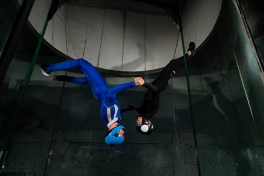 A man and a woman enjoy flying together in a wind tunnel. Free fall simulator.