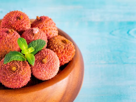 lychee fruit in clay plate on blue wooden background close up