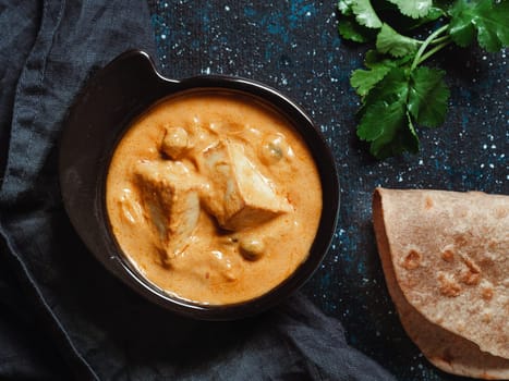 Indian food paneer butter masala in black bowl on dark background. Shahi paneer butter masala or cheese cottage curry top view. Shahi paneer is popular indian lunch or dinner meal. Copy space for text