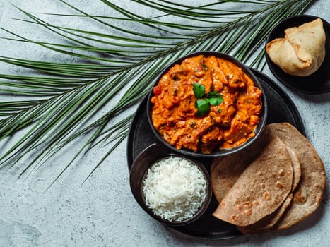 Indian cuisine dishes: tikka masala, rice, samosa, chapati,. Indian food on gray stone background with copy space. Assortment indian meal top view or flat lay.