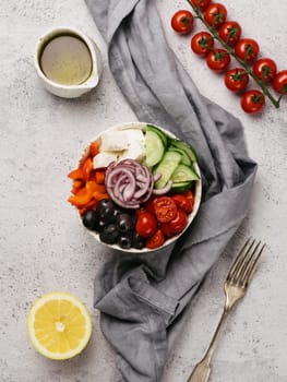 Greek Salad Bowl on gray cement background, copy space. Above view of Bowl Greek Salad. Trendy food. Idea, recept and concept of modern healthy food. Vertical. Toned image.