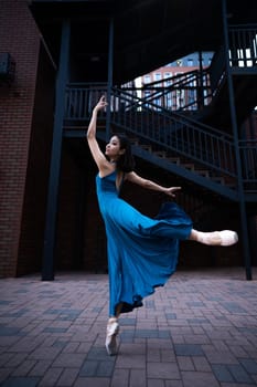 Beautiful Asian ballerina dancing outdoors. Urban landscape