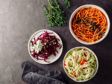 Ideas and recipes for healthy salad - spicy sesame carrot noodles salad,raw beetroot noodles wih ricotta,zucchini zoodles salad with tomatoes.Various vegetarian salads ready-to-eat.Top view.Copy space