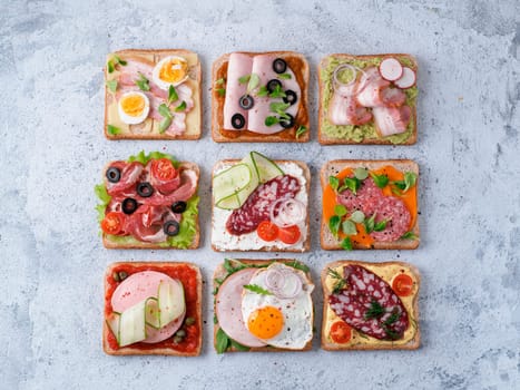 Set of eight different sandwiches with meat in square shape. Top view or flat lay. Assortment meat toasts on gray cement background. Idea, creative concept for sausage maker