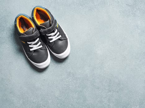 pair of new kids or adult sneakers on gray stone background, top view. Flat lay gray and yellow or mustard color sneakers shoes with copy space for text or design.