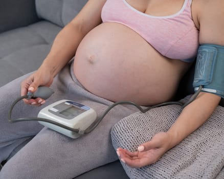 Close-up of the belly of a pregnant woman measuring blood pressure with a tonometer. Hypotension