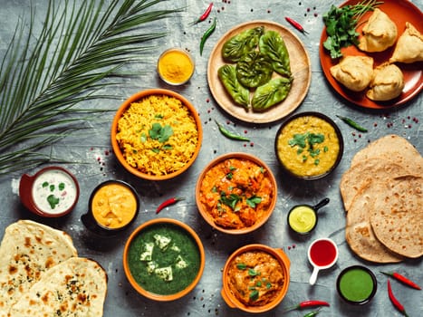 Indian cuisine dishes: tikka masala, dal, paneer, samosa, chapati, chutney, spices. Indian food on gray background. Assortment indian meal top view or flat lay.