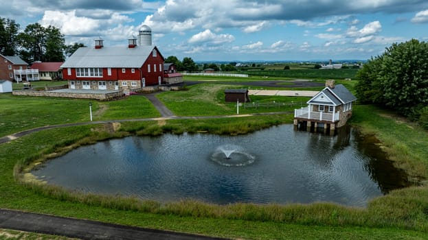 Ronks, Pennsylvania, August 15, 2023 - This idyllic rural scene features a picturesque farmstead complete with a stone gazebo on a pond, capturing the essence of pastoral tranquility.