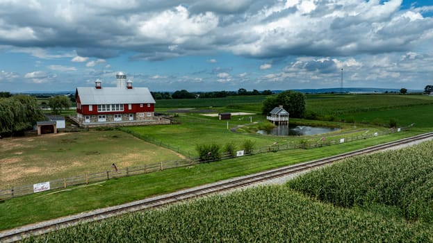 Ronks, Pennsylvania, August 15, 2023 - Dominating this pastoral scene is a classic red barn with a serene pond and gazebo, set against the rich tapestry of flourishing cornfields.