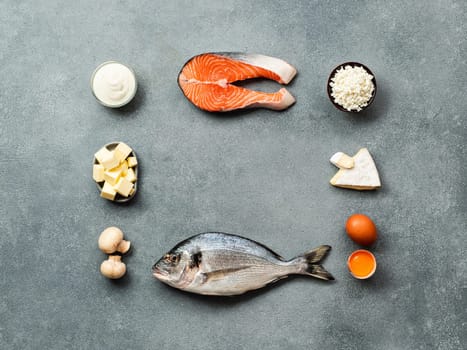 Vaitamin D sources concept with copy space in center. Fish, salmon, dairy products, eggs, mushrooms on gray stone background. Top view or flat lay.