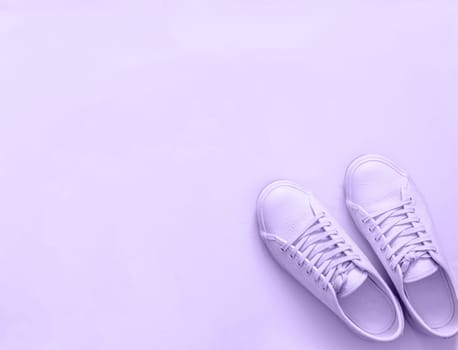 Violet leather sneakers on violet background. Pair of violet sport shoes or sneakers with copy space for text or design. Overhead shot of new violet sneakers,monochrome. Top view or flat lay