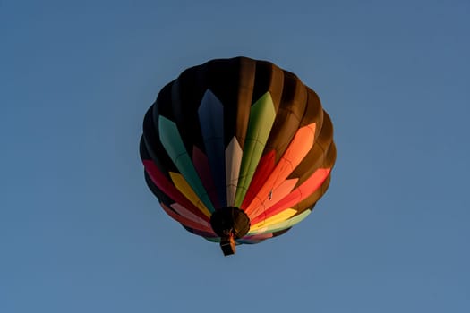 Suspended in the dusk sky, a hot air balloon glows with a kaleidoscope of colors, offering a moment of wonder against the tranquil evening backdrop.