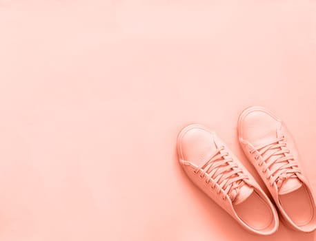 Pink leather sneakers on peach or pink background. Pair of pink sport shoes or sneakers with copy space for text or design. Overhead shot of new pink sneakers,monochrome.Top view or flat lay