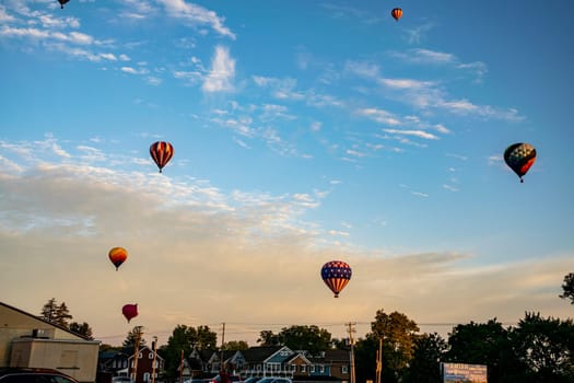 A fleet of vibrant hot air balloons takes to the sky over a local farmer's market at sunset, adding a touch of magic to the day's end.