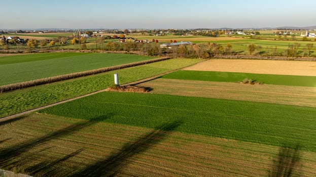 The warm light of the setting sun highlights a patchwork of agricultural fields, presenting a picturesque rural landscape from above.