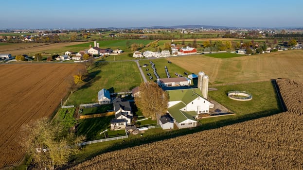 Ronks, Pennsylvania, November 7, 2023 - The warm light of dusk illuminates an expansive farmstead, highlighting the neat rows of crops and the robust agricultural infrastructure from an aerial viewpoint.