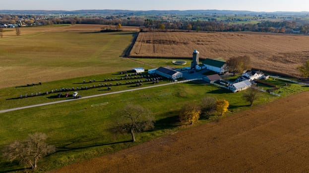 An aerial shot captures the sprawling expanse of a farm at dusk, with fields awaiting harvest and the rural landscape bathed in the soft light of the setting sun.