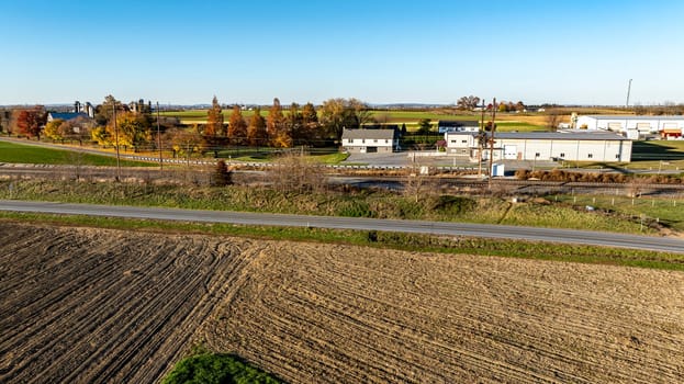 An aerial view captures the essence of harvest season in a rural community with a tapestry of farmland and residential buildings basking in the evening glow.