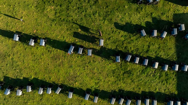 From the sky, the orderly arrangement of Amish buggies casts long shadows on the grass, evoking a sense of community and tradition at day's end. during an Amish Wedding