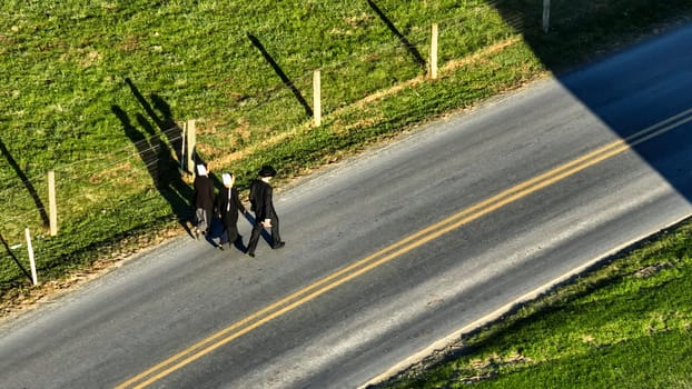 Ronks, Pennsylvania November 14, 2023 - A trio of Amish, walk along a country road, casting long shadows in the afternoon sun, perfect for lifestyle and community themes.