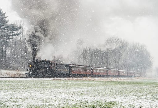 Ronks, Pennsylvania January 6, 2024 - In a picturesque winter scene, a historic steam train cuts through a heavy snowfall, its journey reminiscent of a classic winter's tale.