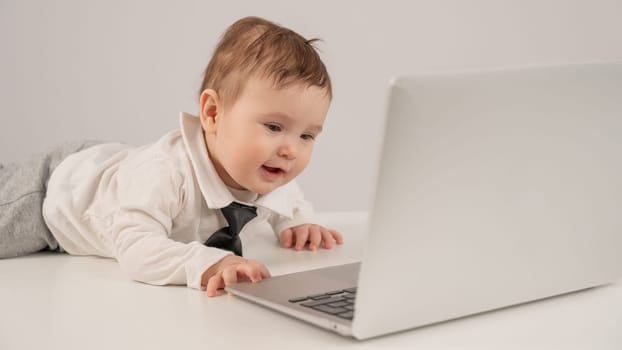 Cute baby boy in a tie working at a laptop