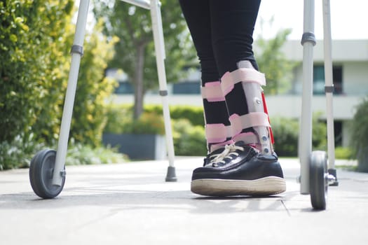 child with walking frame and knee orthosis outdoor .