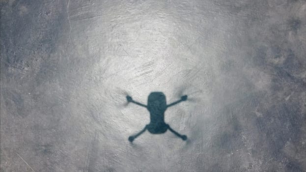 Shadow of a small drone on the pavement