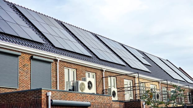 row of family homes new houses with black solar panels on the roof, Close up of new building with black solar panels. Zonnepanelen, Zonne energie, Translation: Solar panel, Sun Energy