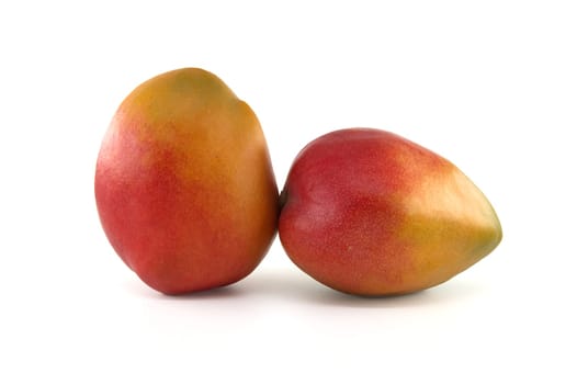 Two ripe mango fruits with a blend of red and yellow tones on their skin isolated against a white background