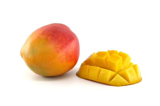 Ripe mango with crimson and yellow skin close to sliced half of a mango with cubed meat