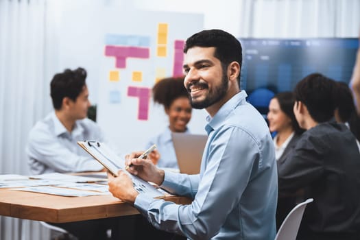 Portrait of happy and smiling businessman with group of coworkers on meeting with screen display business dashboard in background. Confident office worker at team meeting. Concord