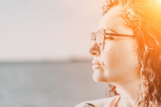 Portrait of a curly woman in glasses on the background of the sea. Vacation on the sea, walk, tourism