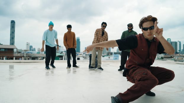 Professional asian street dancer practice B boy dance while multicultural friends at roof top. Young modern dancing group doing hip hop movement. Style,fashion,action. Outdoor sport 2024. Endeavor.