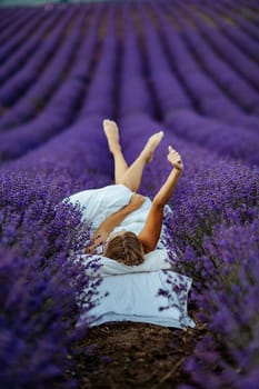 A middle-aged woman lies in a lavender field and enjoys aromatherapy. Aromatherapy concept, lavender oil, photo session in lavender.