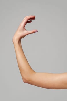 Female hand sign against gray background in studio close up