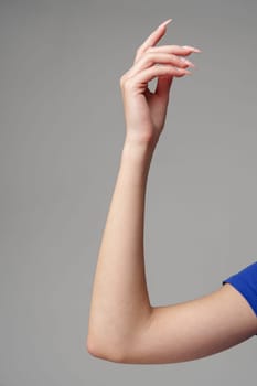 Female hand sign against gray background in studio close up