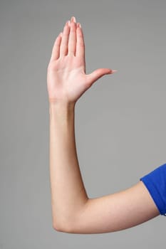 Female hand sign against gray background in studio close up