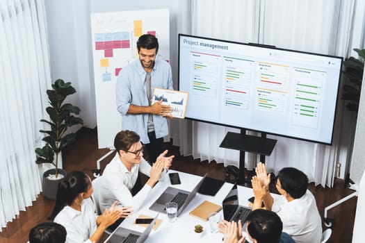 Project manager communicate and collaborate with team using project management software display on monitor, tracking progress of project task and making schedule plan at meeting table. Prudent