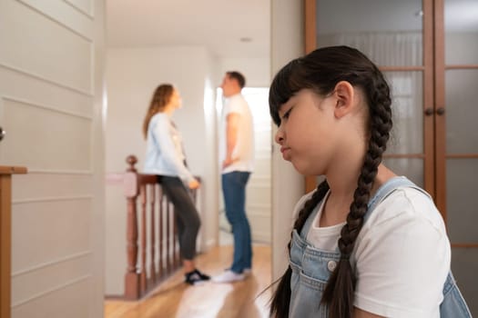 Stressed and unhappy young girl huddle in corner crying and sad while her parent arguing in background. Domestic violence at home and traumatic childhood develop to depression. Synchronos