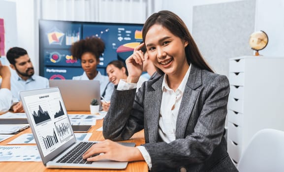 Portrait of happy young asian businesswoman with group of office worker on meeting with screen display business dashboard in background. Confident office lady at team meeting. Concord