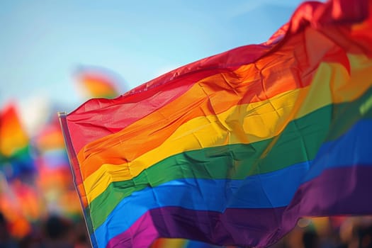 A rainbow LGBT flag flies against a blue sky.