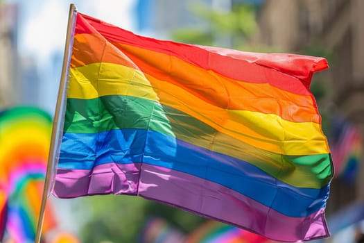 A rainbow LGBT flag flies against a blue sky.